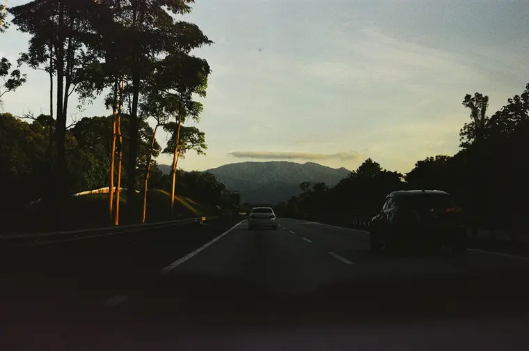 A highway at dusk heading toward distant hills