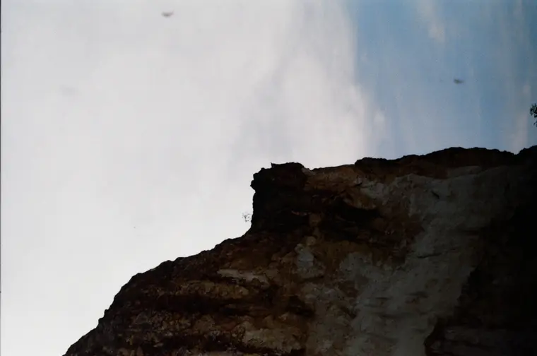 Dark cliff edge against a bright white sky