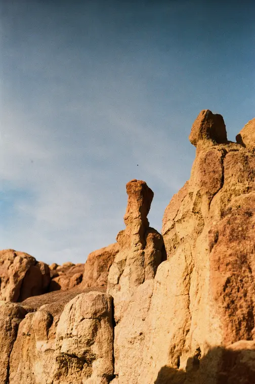 A thin orange rock spire against a blue sky