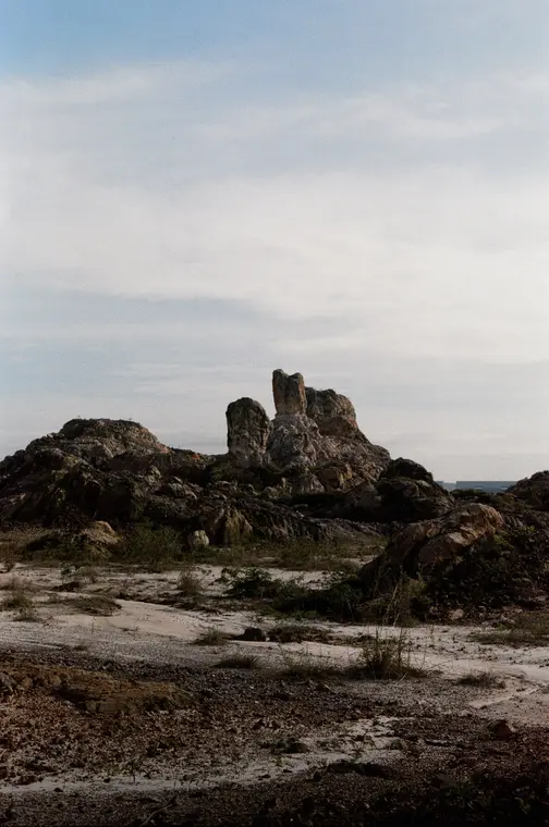 Rock formations above cracked pale ground under a grey sky