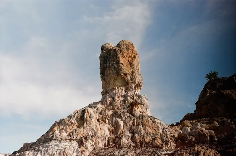 A single rock pillar on a pink and white mound