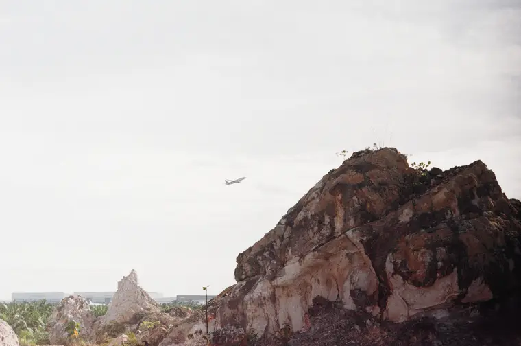 A plane crossing the sky above a pink rock outcrop